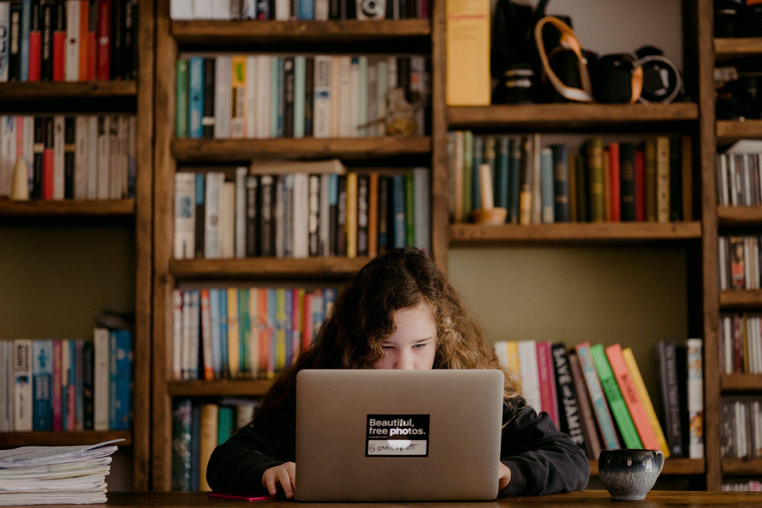 Child displaying curiosity researching Covid on Computer surrounded by books